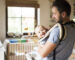 happy father with baby in baby carrier at home